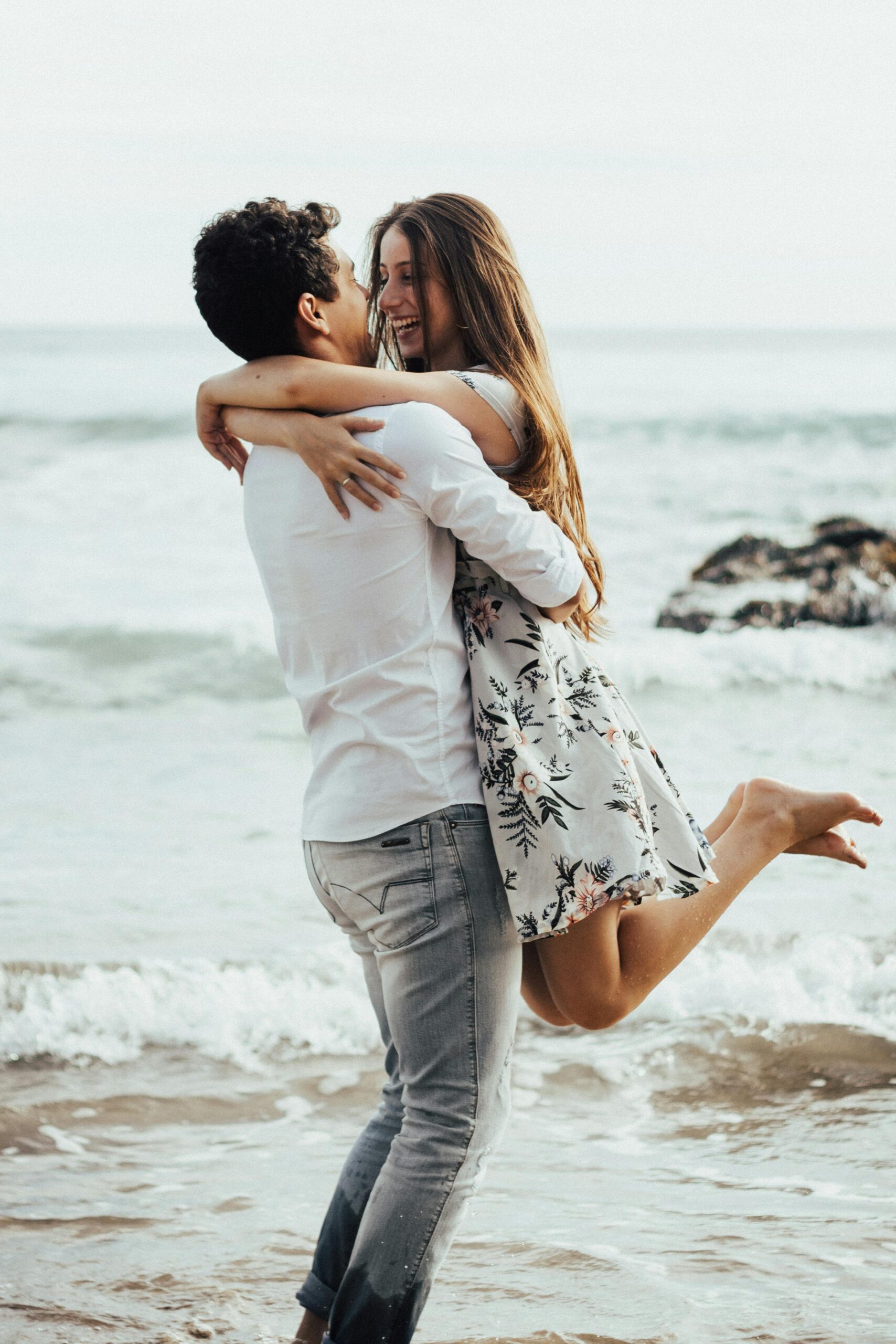 Happy couple in love embracing on a sandy beach by the ocean.